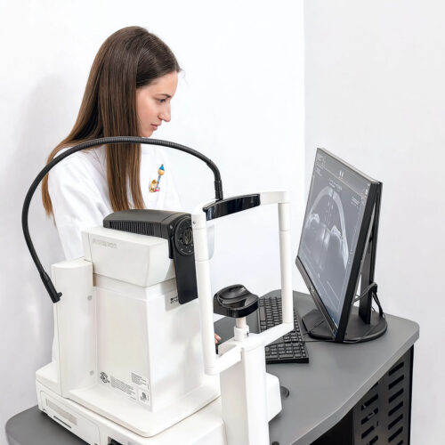 Oculista utilizza uno strumento OCT per la scansione oculare, con immagine della tomografia visibile a monitor