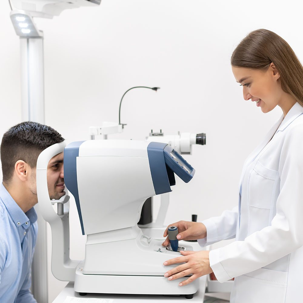 Paziente sottoposto ad esame con autorefrattometro per la misurazione dei difetti visivi, oculista sorridente regola lo strumento