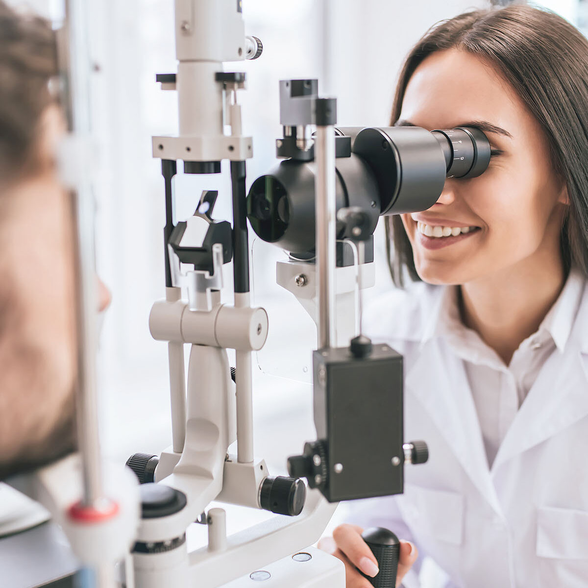 Oculista sorridente esamina un paziente con la lampada a fessura per la diagnosi dei difetti visivi