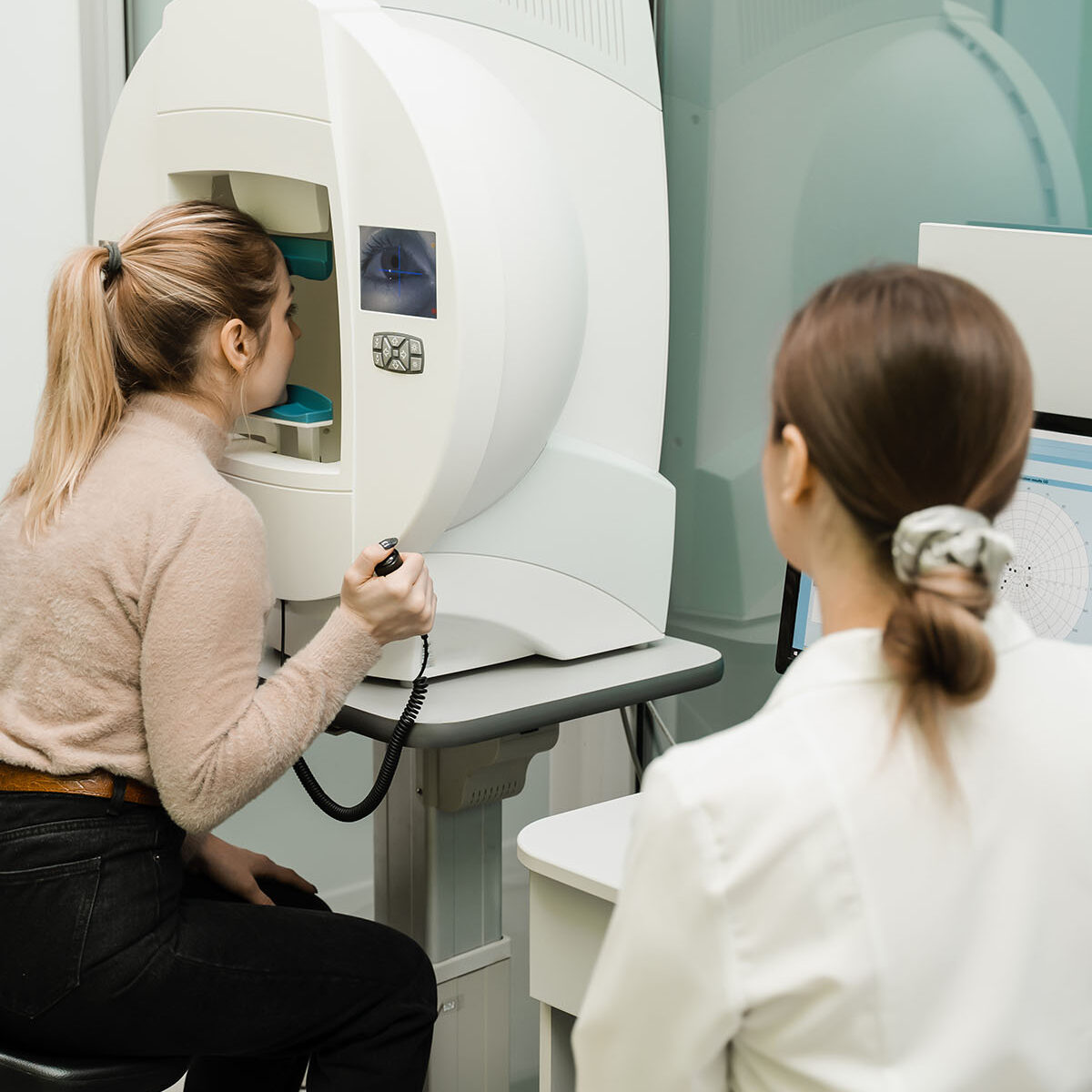 Paziente sottoposta a esame del campo visivo per il glaucoma, oculista monitora i risultati sul computer