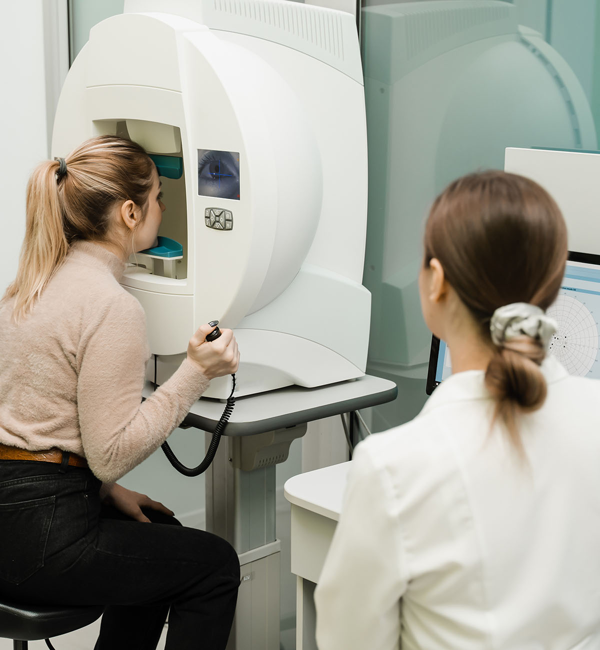 Paziente sottoposta a esame del campo visivo per il glaucoma, oculista monitora i risultati sul computer