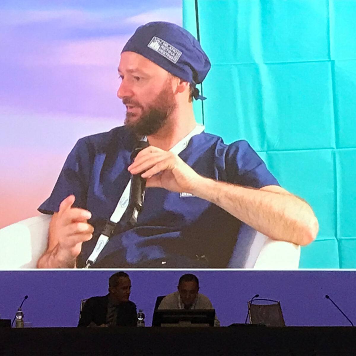 Matteo Cereda interviene come relatore a un congresso di oftalmologia, ripreso sul maxischermo della sala.